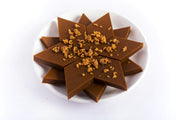 A plate of Karuppati Premium Kaju Katli, which are star-shaped dessert squares topped with nuts.